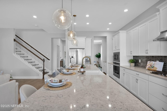 kitchen with white cabinets, light stone counters, appliances with stainless steel finishes, and a sink