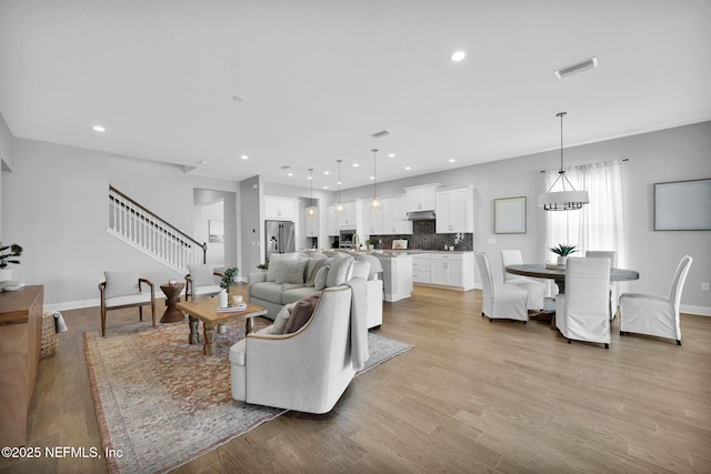 living room with stairs, recessed lighting, light wood-style floors, and visible vents