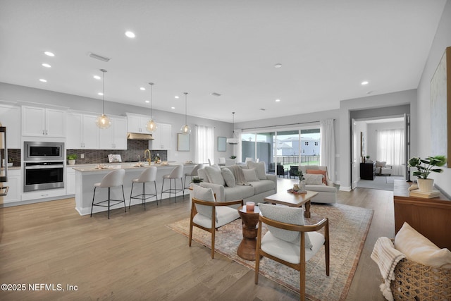 living area with visible vents, recessed lighting, and light wood-type flooring