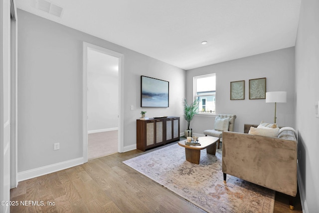 living room featuring visible vents, baseboards, and wood finished floors