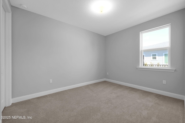 spare room with baseboards and carpet