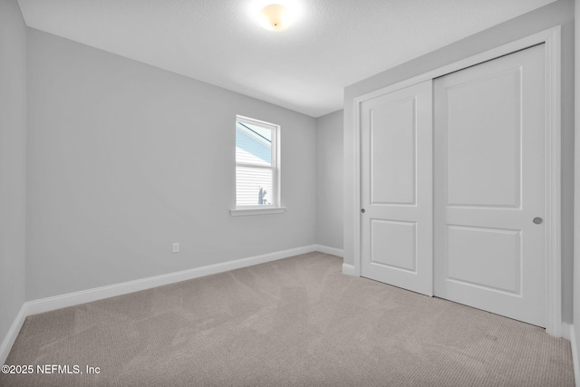 unfurnished bedroom with carpet flooring, baseboards, and a closet