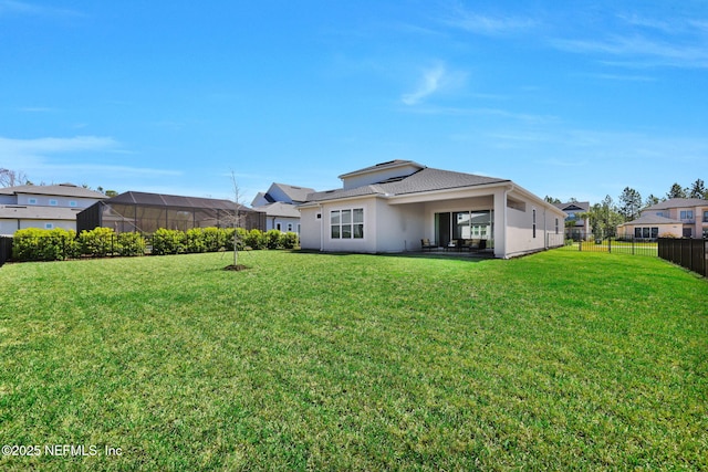 back of property featuring stucco siding, a lawn, and fence