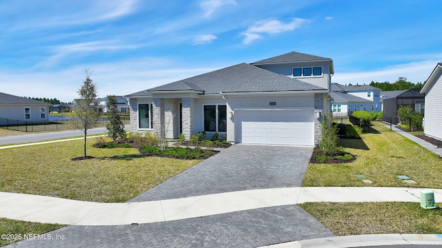 prairie-style home with stucco siding, a front lawn, a garage, stone siding, and decorative driveway