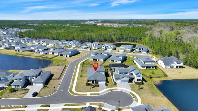 aerial view featuring a view of trees, a residential view, and a water view