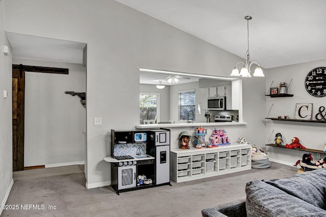 living area featuring baseboards, vaulted ceiling, a barn door, carpet flooring, and ceiling fan with notable chandelier