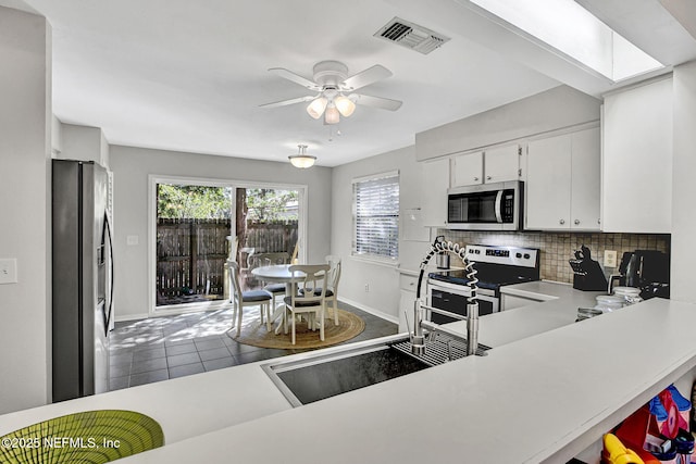 kitchen featuring tasteful backsplash, visible vents, light countertops, appliances with stainless steel finishes, and a ceiling fan