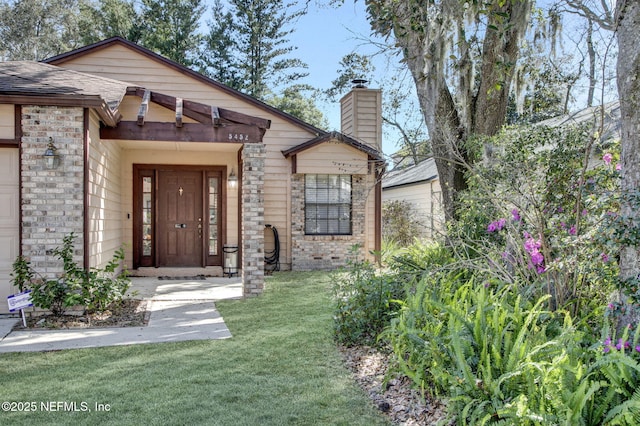 view of exterior entry with a chimney, a yard, a shingled roof, a carport, and brick siding