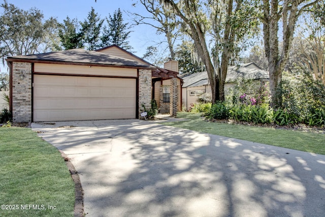 view of front facade featuring concrete driveway, a front yard, a garage, brick siding, and a chimney