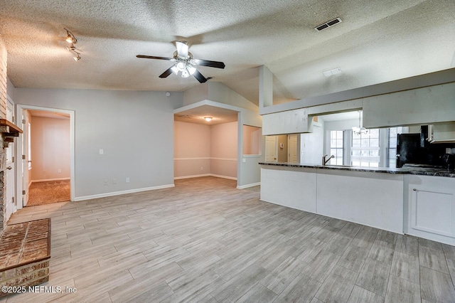 kitchen with vaulted ceiling, white cabinets, a ceiling fan, and light wood-style flooring