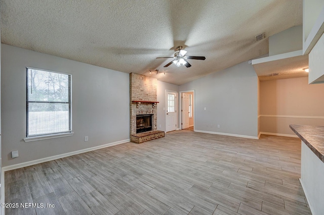 unfurnished living room with light wood finished floors, visible vents, a fireplace, and a ceiling fan