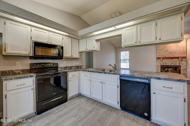 kitchen with a sink, white cabinetry, black appliances, and vaulted ceiling