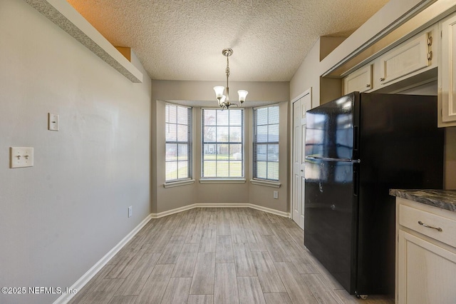 kitchen with a chandelier, vaulted ceiling, freestanding refrigerator, light wood-style floors, and hanging light fixtures