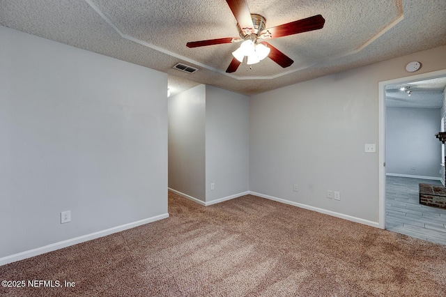 carpeted spare room featuring baseboards, visible vents, a textured ceiling, and ceiling fan