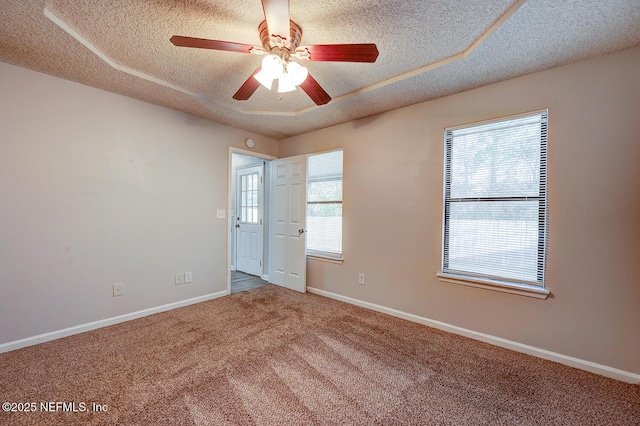 carpeted spare room featuring baseboards, a textured ceiling, and ceiling fan