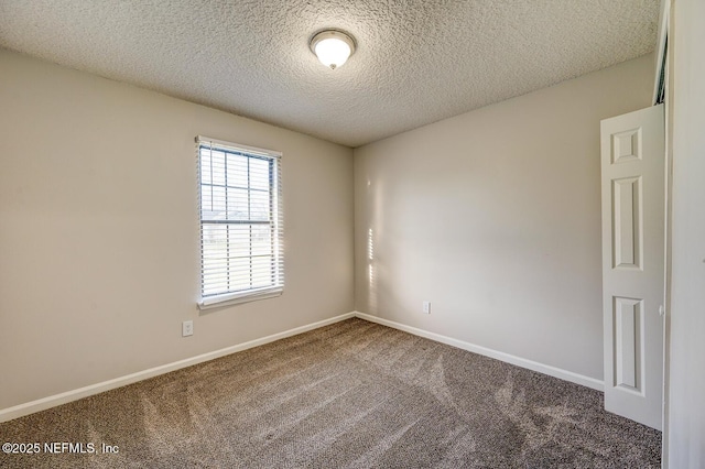 spare room with a textured ceiling, baseboards, and carpet