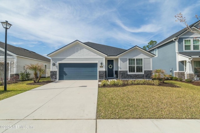 craftsman house featuring stone siding, an attached garage, concrete driveway, and a front lawn