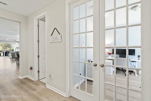 doorway with visible vents, baseboards, wood finished floors, and french doors