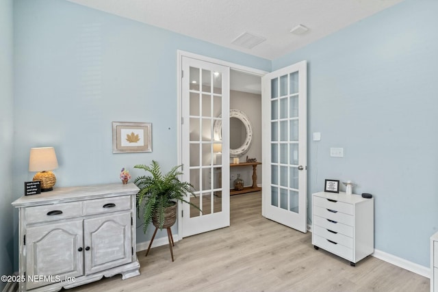 living area with visible vents, french doors, light wood-style floors, and baseboards