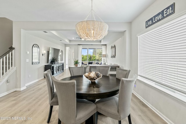 dining room with stairs, light wood-style floors, baseboards, and a chandelier