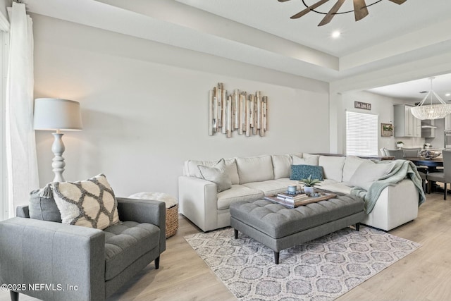 living area with recessed lighting, light wood-style flooring, and ceiling fan with notable chandelier