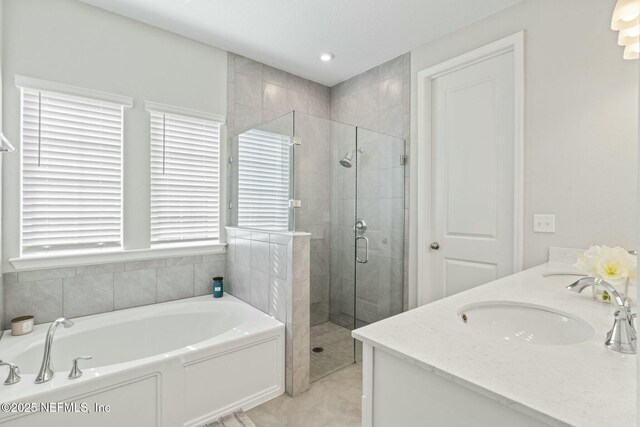 full bathroom with double vanity, recessed lighting, a sink, a shower stall, and a garden tub