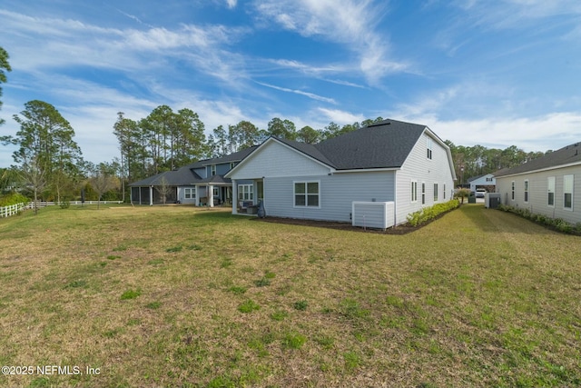 rear view of house with fence and a lawn