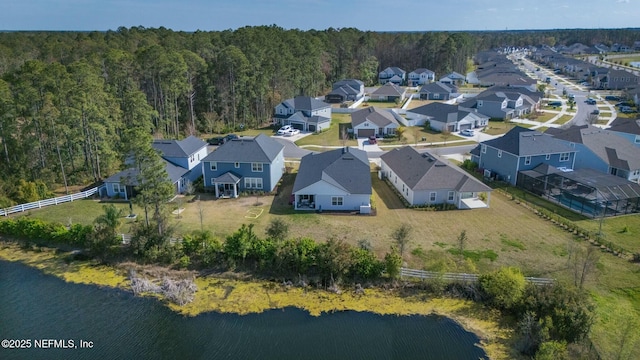 drone / aerial view with a residential view, a wooded view, and a water view