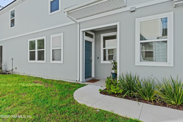 property entrance featuring a yard and stucco siding