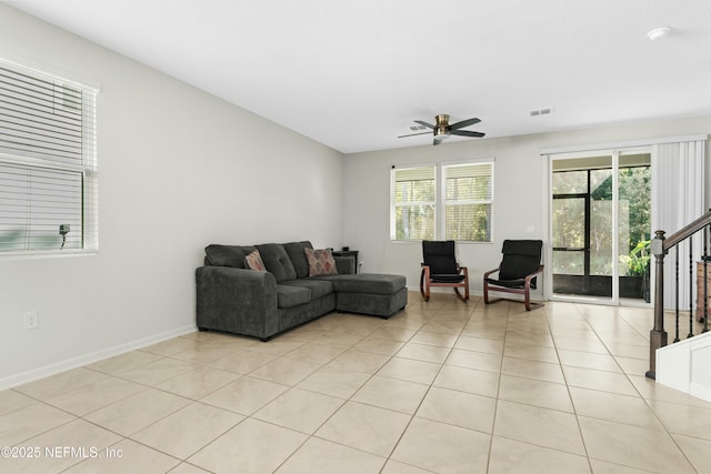 living room featuring light tile patterned floors, a healthy amount of sunlight, stairs, and a ceiling fan