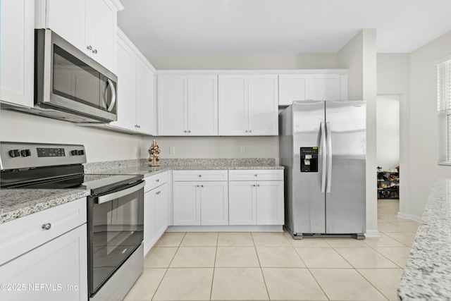 kitchen with light tile patterned floors, stainless steel appliances, light stone counters, and white cabinetry