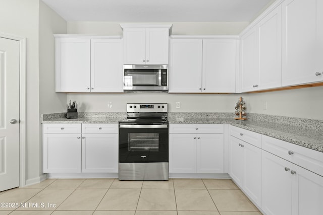 kitchen with white cabinets, light tile patterned floors, light stone countertops, and appliances with stainless steel finishes