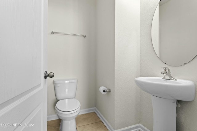 half bathroom with tile patterned flooring, toilet, and baseboards