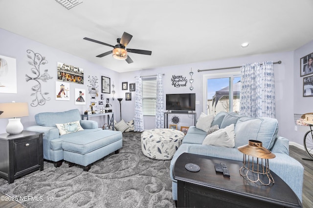 living area with baseboards, wood finished floors, visible vents, and ceiling fan