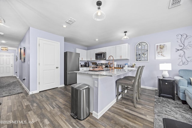 kitchen featuring visible vents, dark wood-type flooring, light stone countertops, appliances with stainless steel finishes, and white cabinets