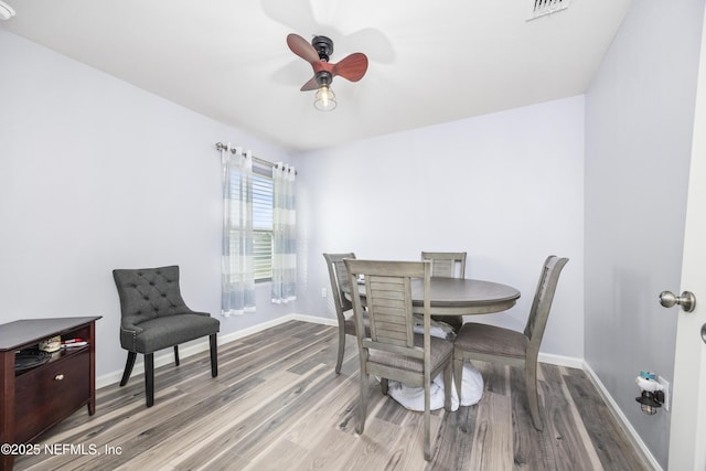 dining area featuring visible vents, baseboards, wood finished floors, and a ceiling fan