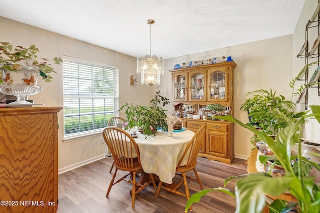 dining space with a notable chandelier, baseboards, light wood-type flooring, and a textured ceiling