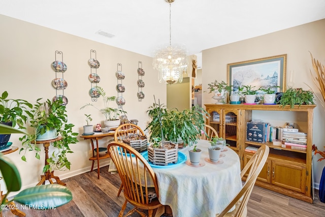 dining space with light wood finished floors, visible vents, baseboards, and an inviting chandelier