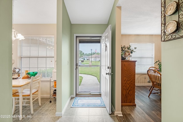 foyer entrance featuring tile patterned floors, baseboards, and a notable chandelier