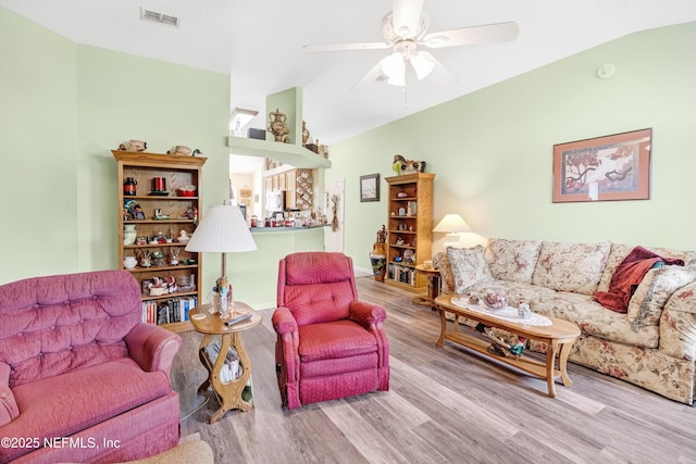 living room with visible vents, lofted ceiling, wood finished floors, and a ceiling fan