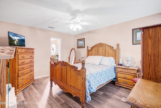 bedroom featuring baseboards, wood finished floors, visible vents, and ceiling fan