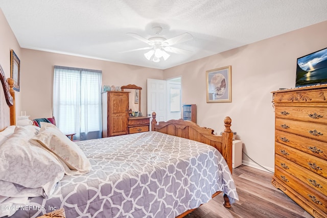 bedroom featuring ceiling fan, wood finished floors, and a textured ceiling