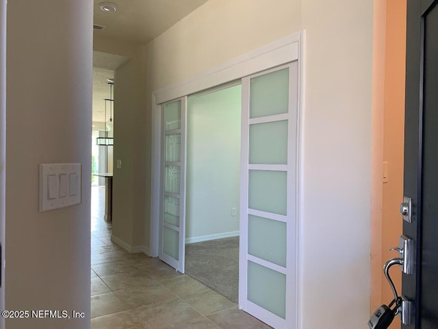 hall featuring baseboards and light tile patterned flooring