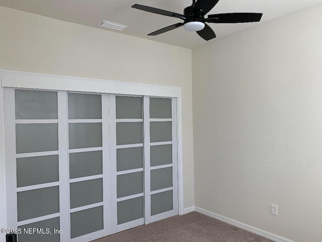 carpeted spare room featuring visible vents, baseboards, and a ceiling fan