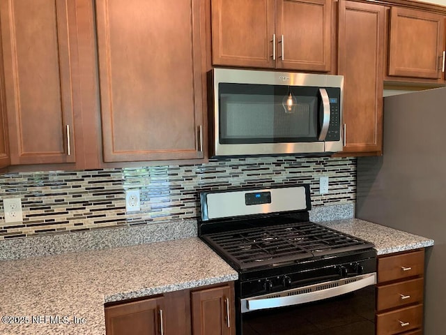 kitchen with backsplash, appliances with stainless steel finishes, and light stone countertops