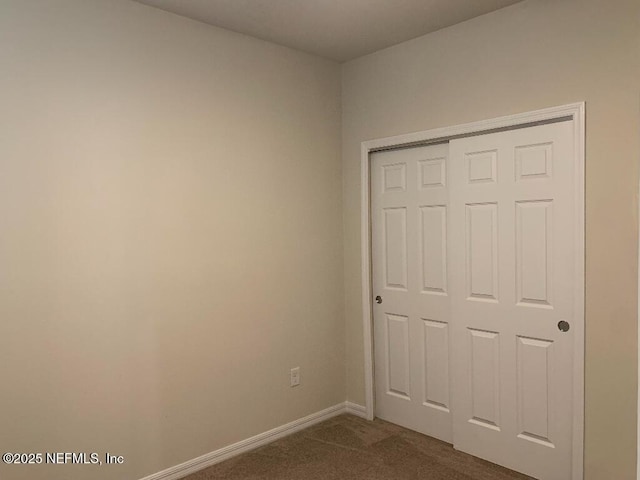 unfurnished bedroom with a closet, baseboards, and carpet