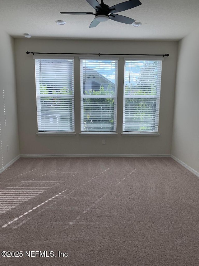 unfurnished room with baseboards, carpet floors, and a ceiling fan