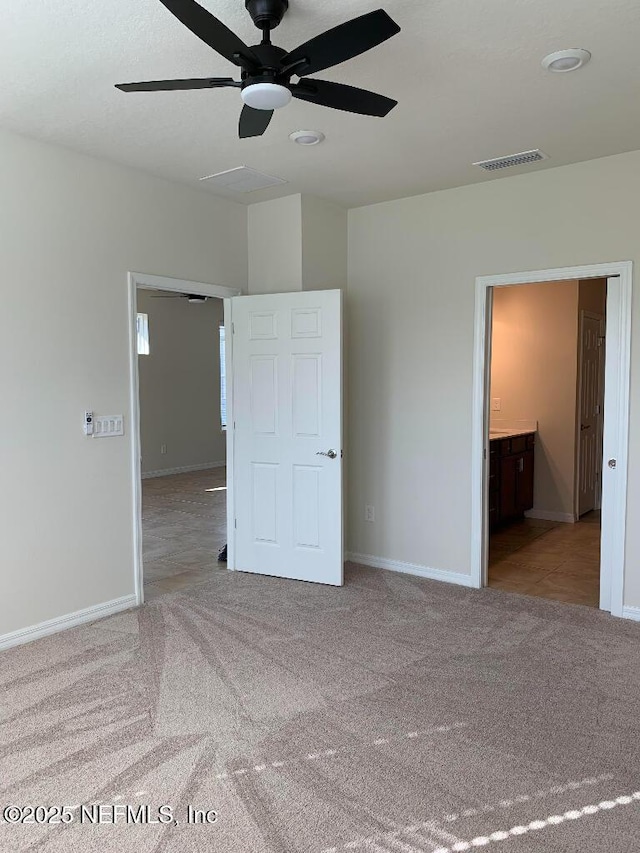 unfurnished bedroom with visible vents, a ceiling fan, ensuite bath, carpet, and baseboards