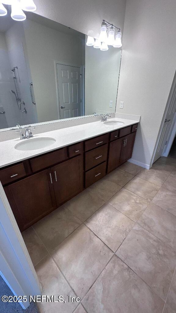 bathroom featuring a sink, baseboards, a chandelier, and double vanity