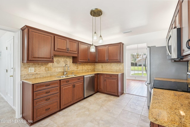 kitchen featuring tasteful backsplash, visible vents, decorative light fixtures, appliances with stainless steel finishes, and a sink